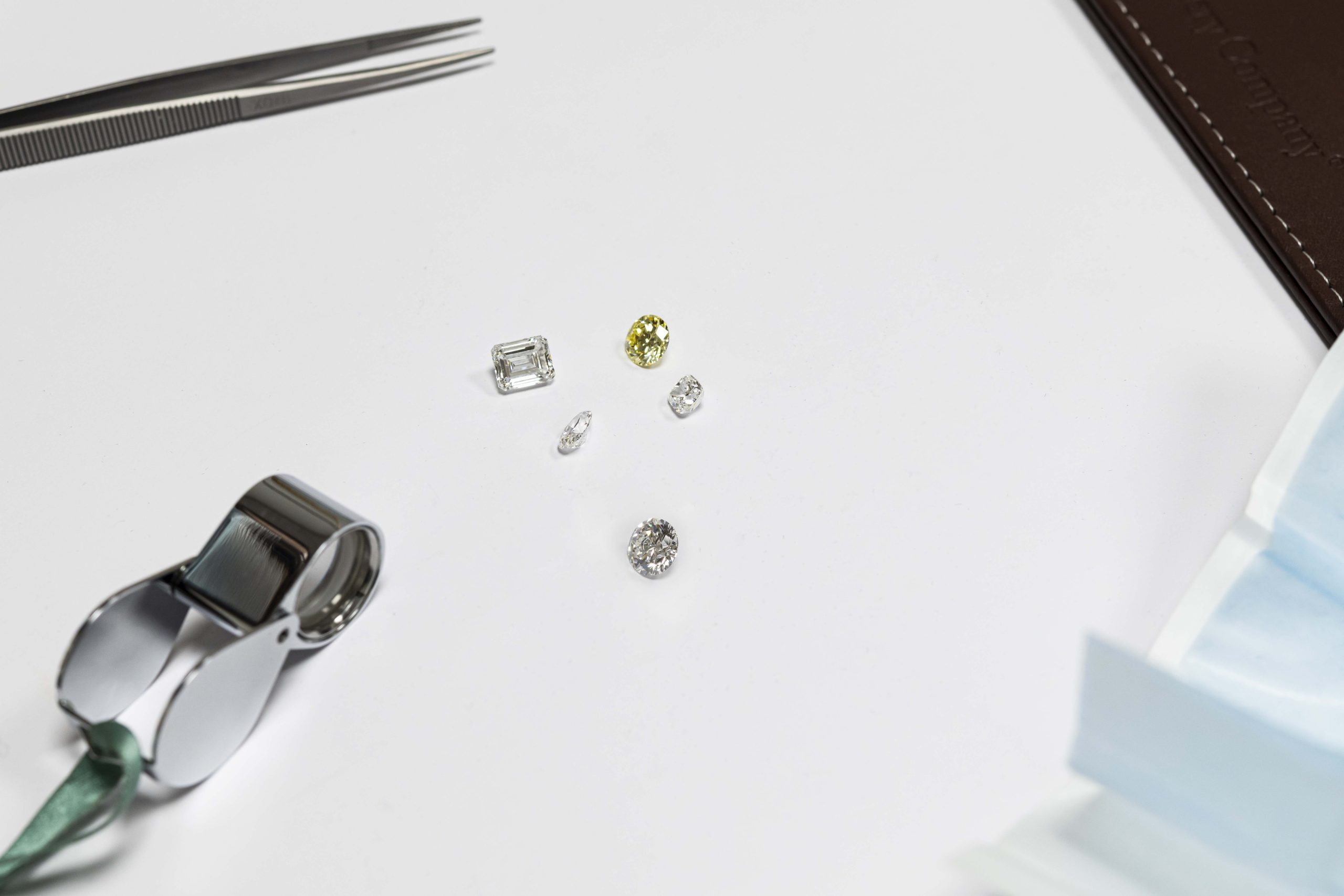 Loose polished diamonds and a loupe on the white viewing surface