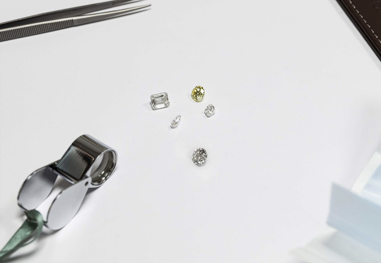 Polished diamonds and a loupe laid out on the white working surface during a course