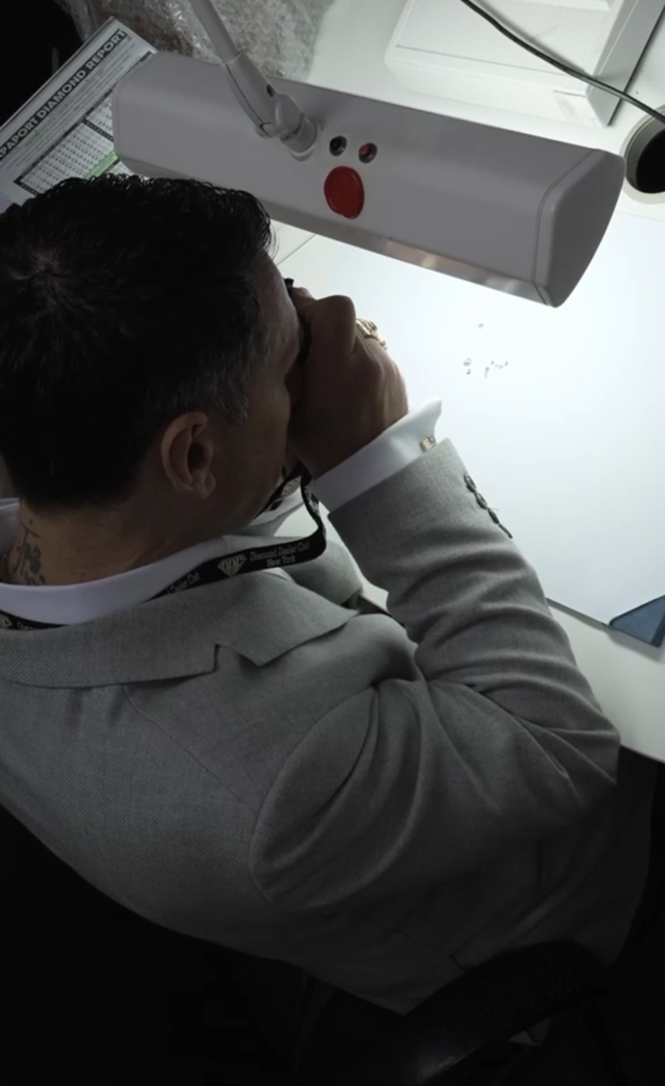 A member at a microscope examining a stone under a lamp at the Bourse